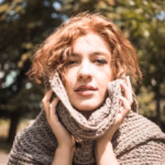 young-woman-touching-face-with-scarf-park_23-2147911423